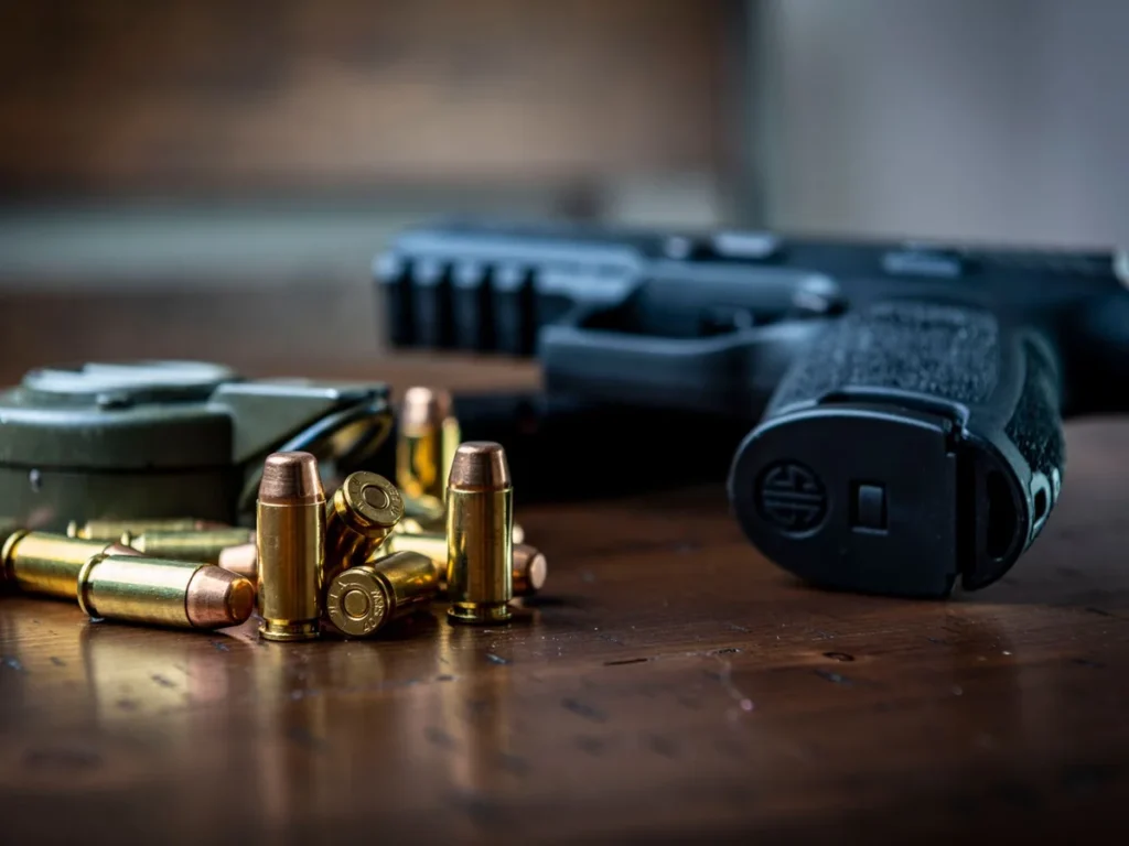 Handgun and cartridges on a wooden work surface