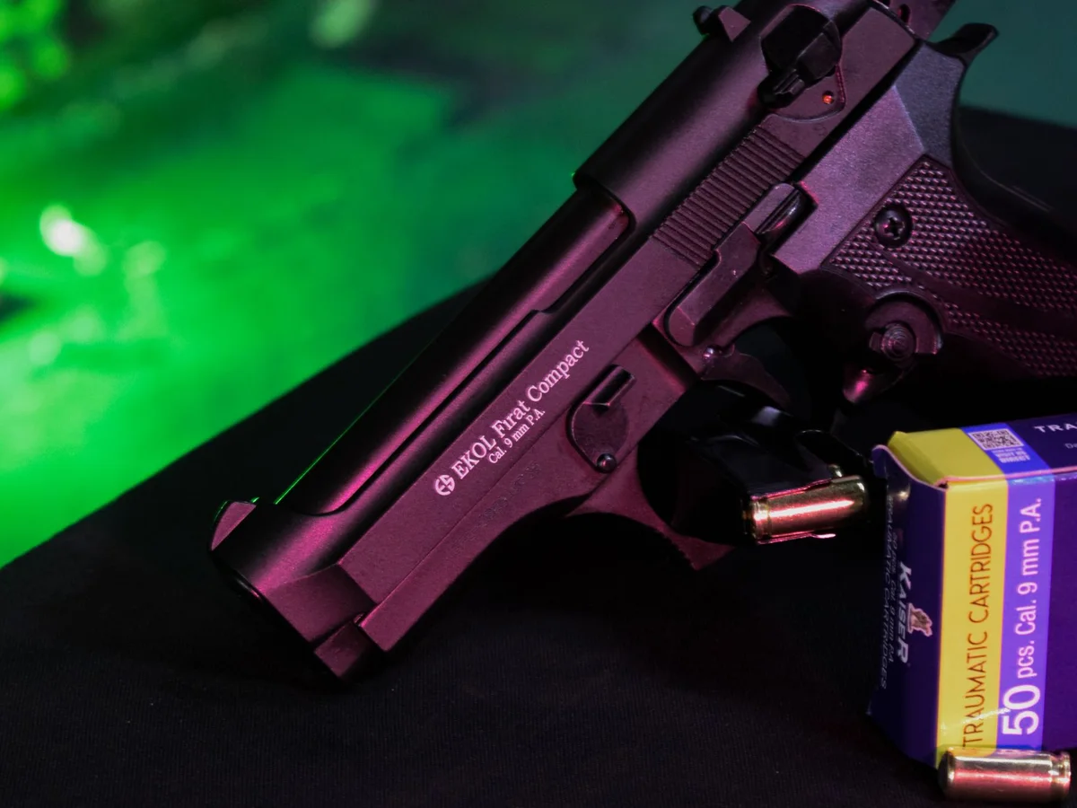 Handgun, magazine, and ammunition on a green work surface