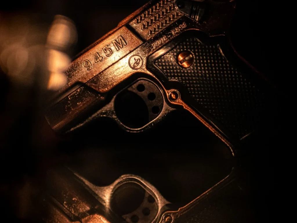 Low-light close-up of a handgun on a reflective surface