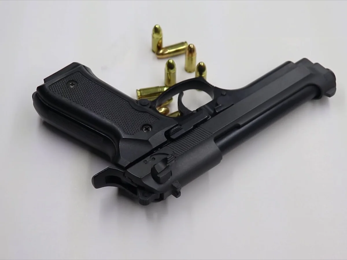 Handgun and cartridges arranged on a light surface