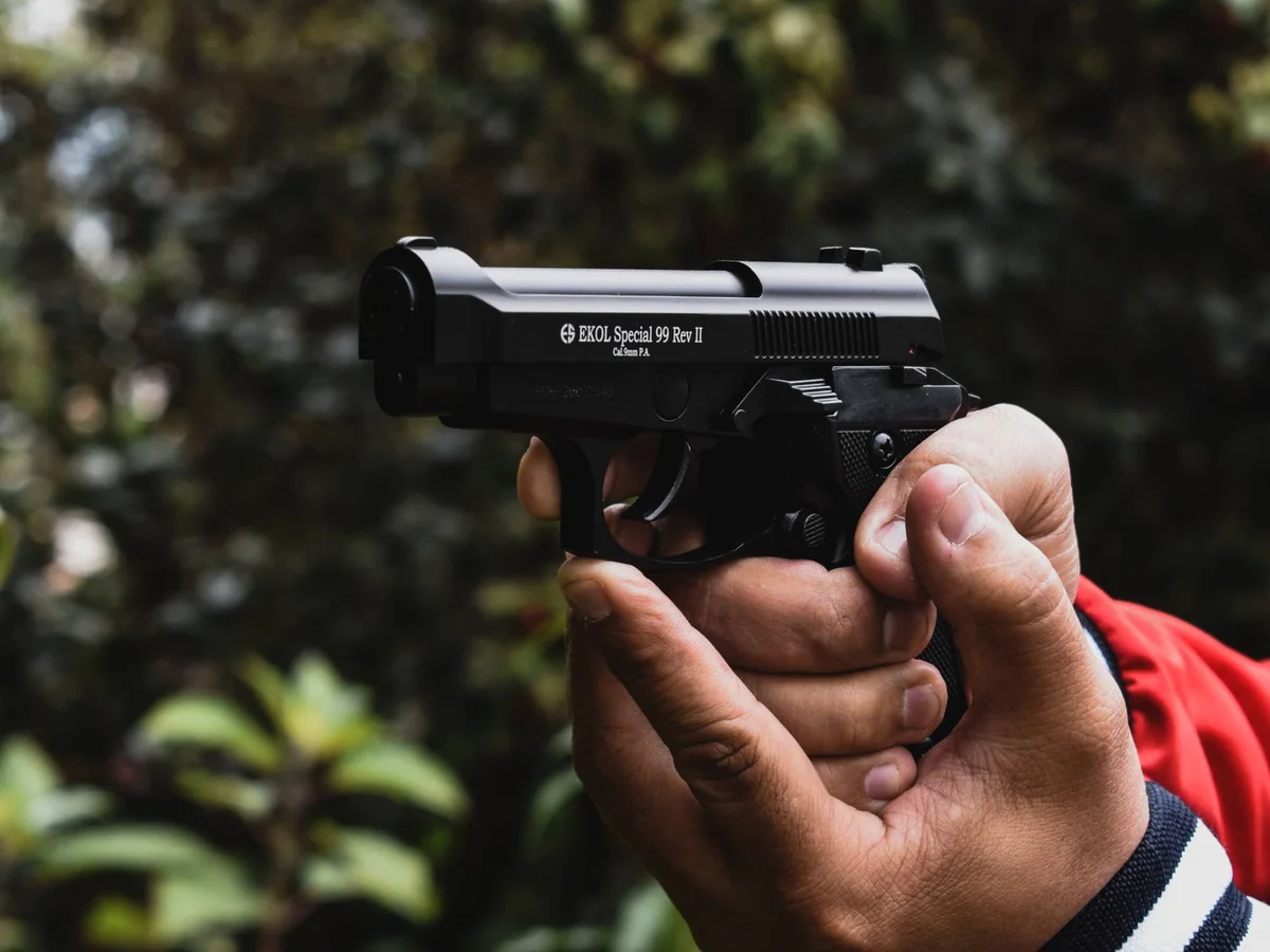 Close-up of a handgun grip against an outdoor background