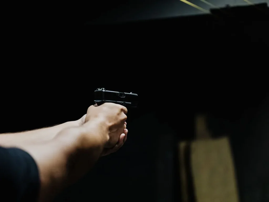 Arm aiming a handgun in a dark shooting environment
