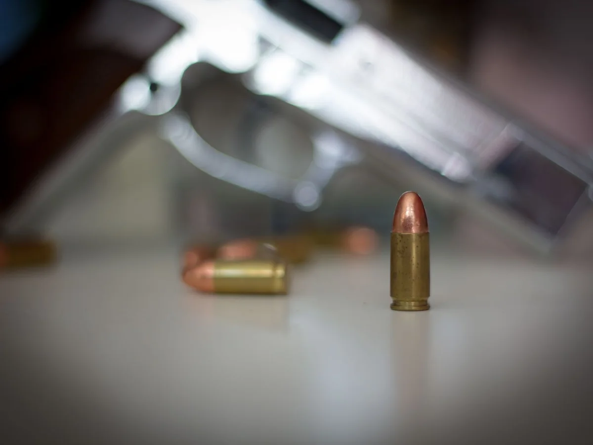 Cartridge in focus with a handgun in the background